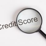 A magnifying glass hovering over the words "Credit Score" to illustrate analyzing a Business Credit Portfolio.