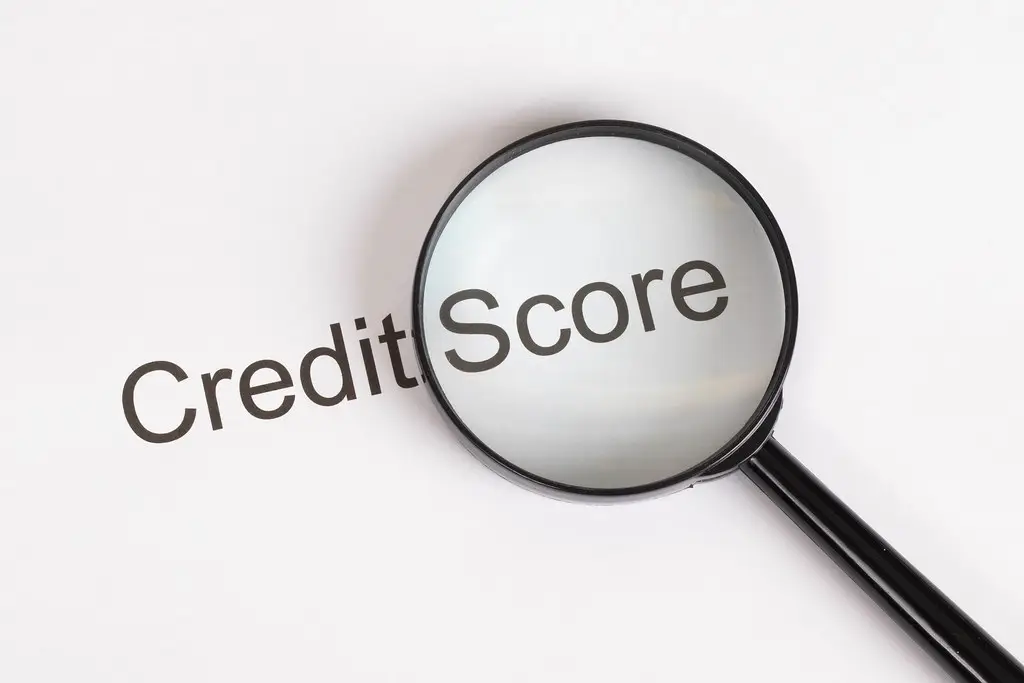A magnifying glass hovering over the words "Credit Score" to illustrate analyzing a Business Credit Portfolio.